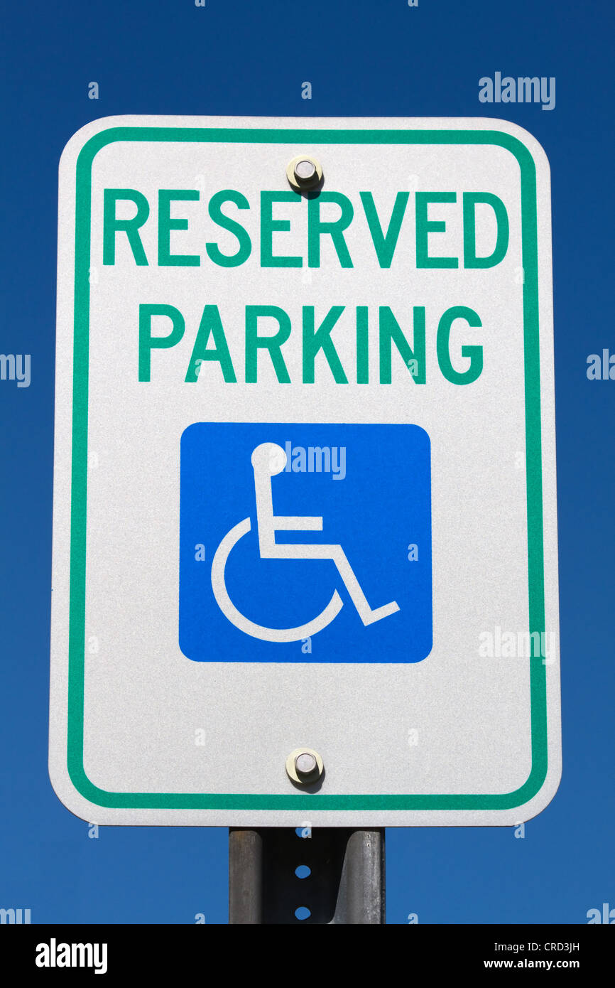 Disabled and handicapped reserved parking sign against a blue sky. Stock Photo