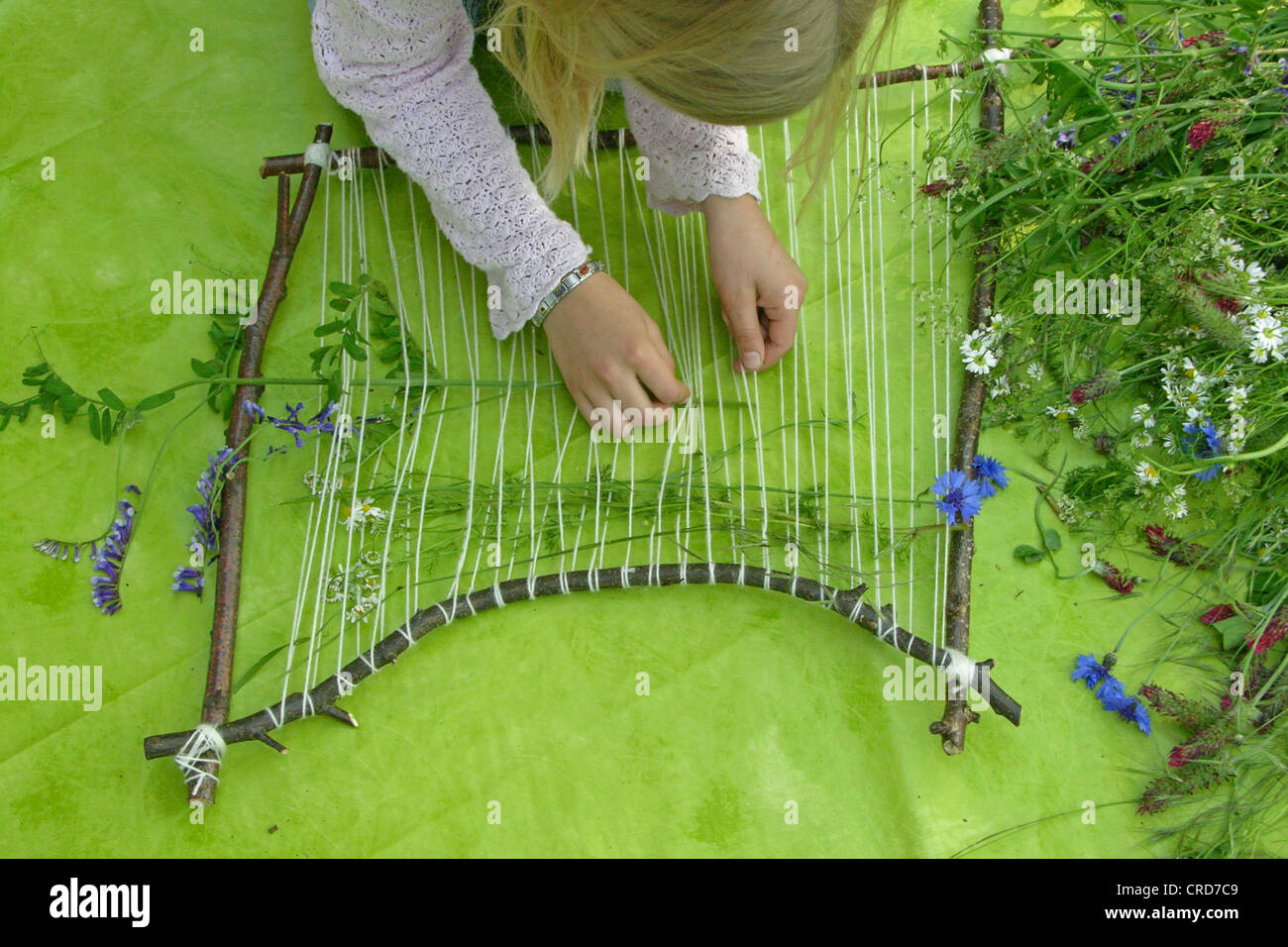 little girl building a picture frame with twigs and flowers, series picture 5/7 Stock Photo