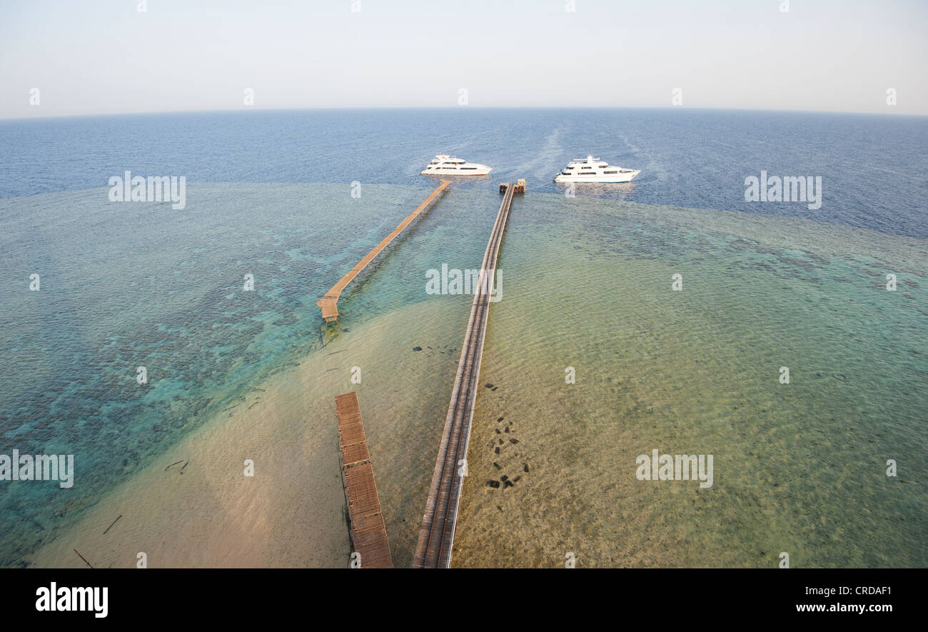 Aerial view of two private motor yachts moored at an offshore tropical reef with open ocean background Stock Photo