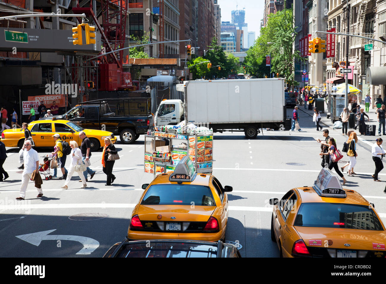 Iconic yellow taxis waiting at the lights while a food cart goes by in ...