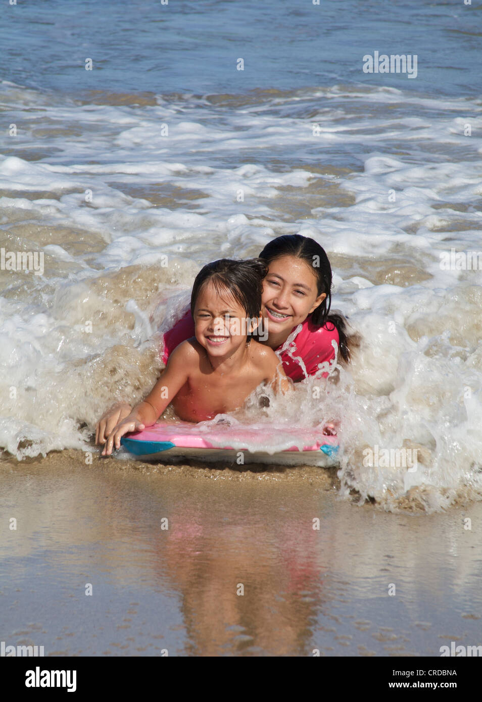 Brother and sister on boogie board at Hanalei Beach on Kauai Stock Photo