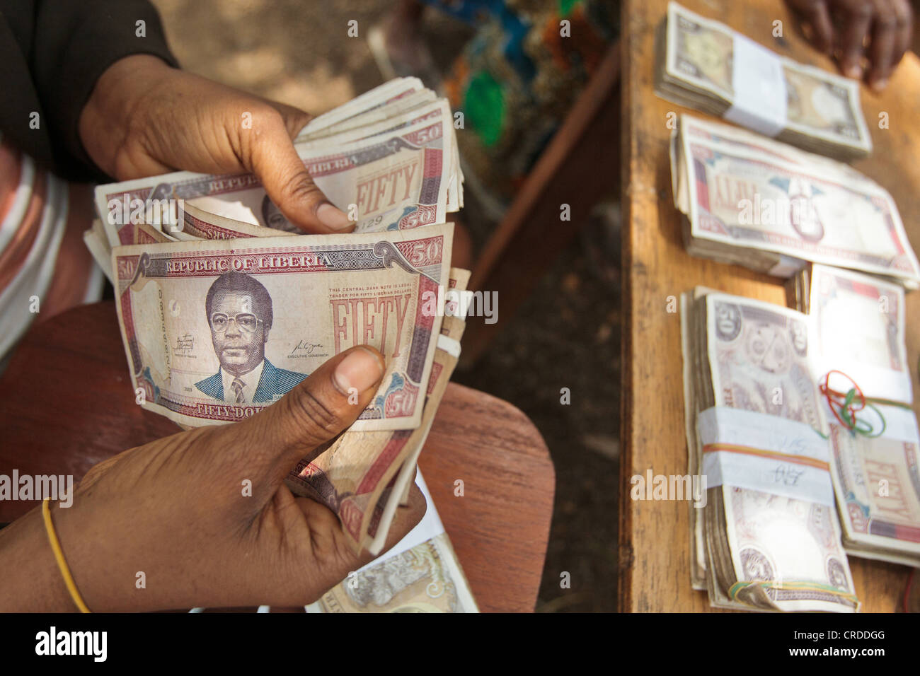 A staff member from a local bank counts money during a social cash transfer programme distribution Stock Photo