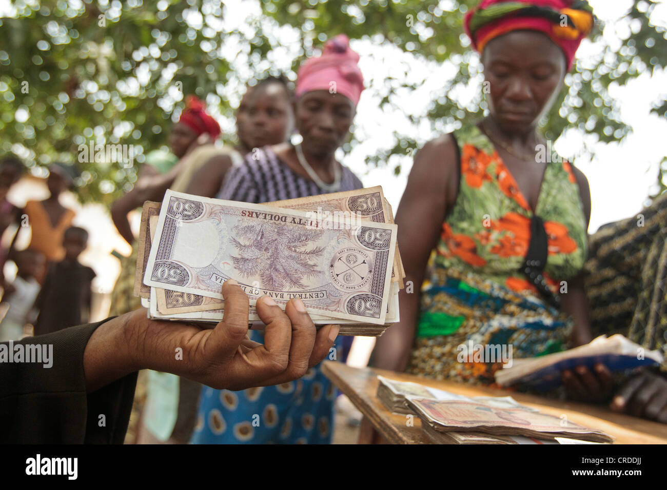 A staff from a local bank holds a handfull of money during a social cash transfer programme distribution Stock Photo