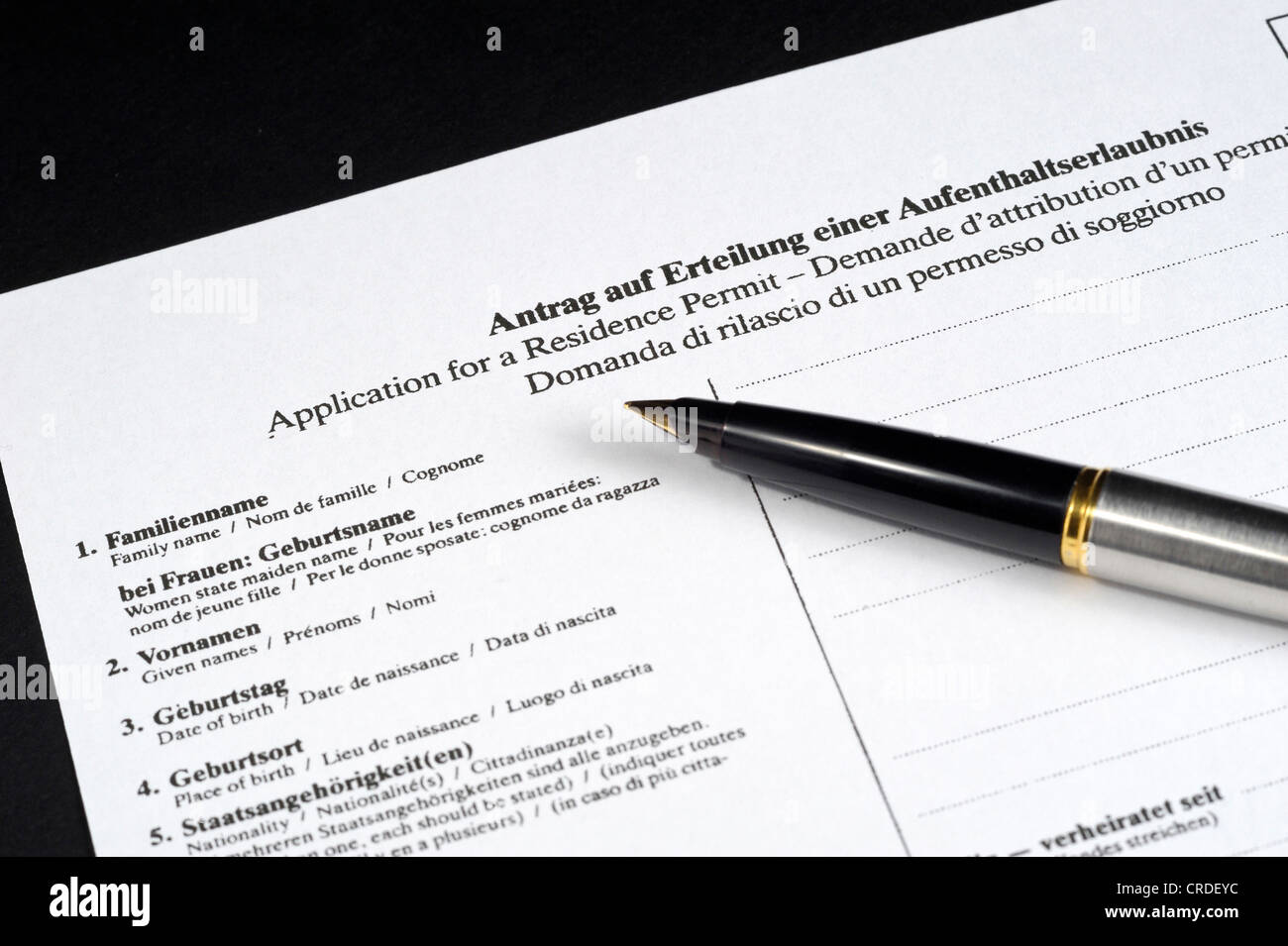 Application for a residence permit in German, English, French and Italian, with pen Stock Photo