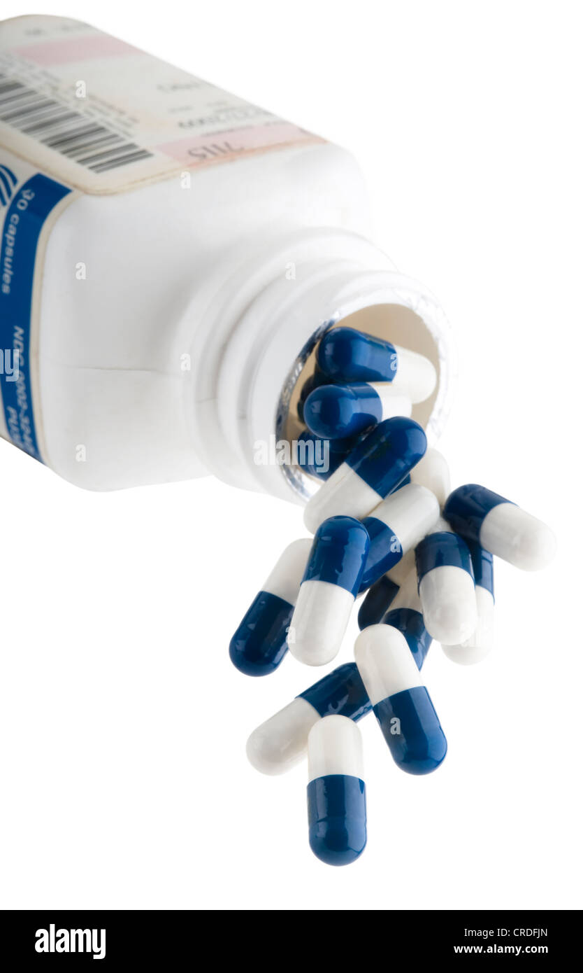 Blue and White capsules spilling out of prescription bottle Stock Photo