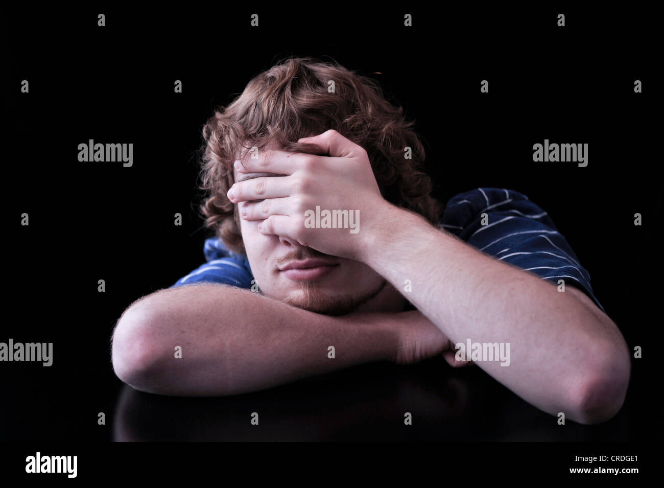 Young man covering face with his hand Stock Photo - Alamy