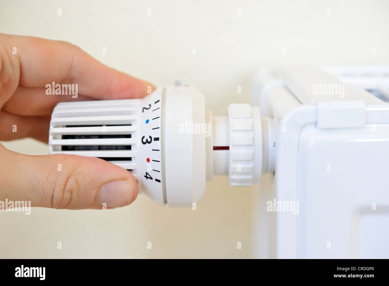 Hand adjusting the temperature on a thermostatic valve of a radiator