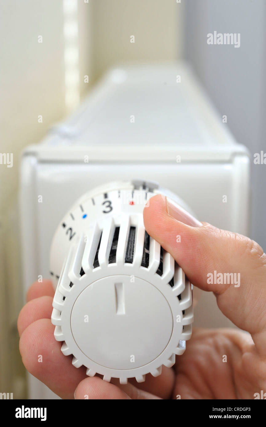 Hand adjusting the temperature on a thermostatic valve of a radiator Stock Photo