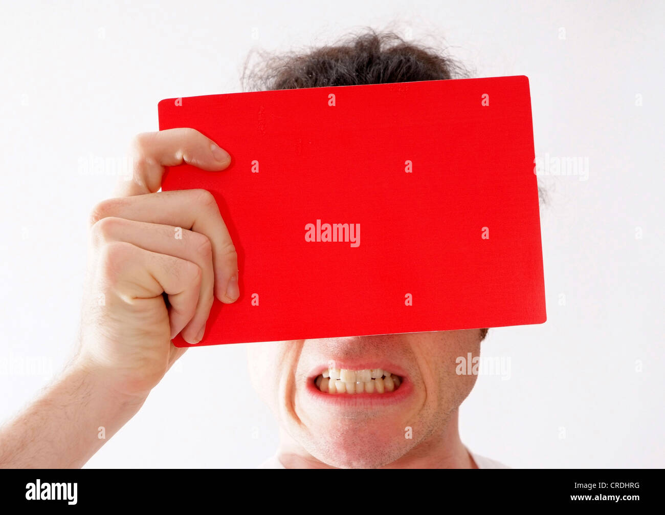 man showing red card in front of his face, displaying teeth Stock Photo