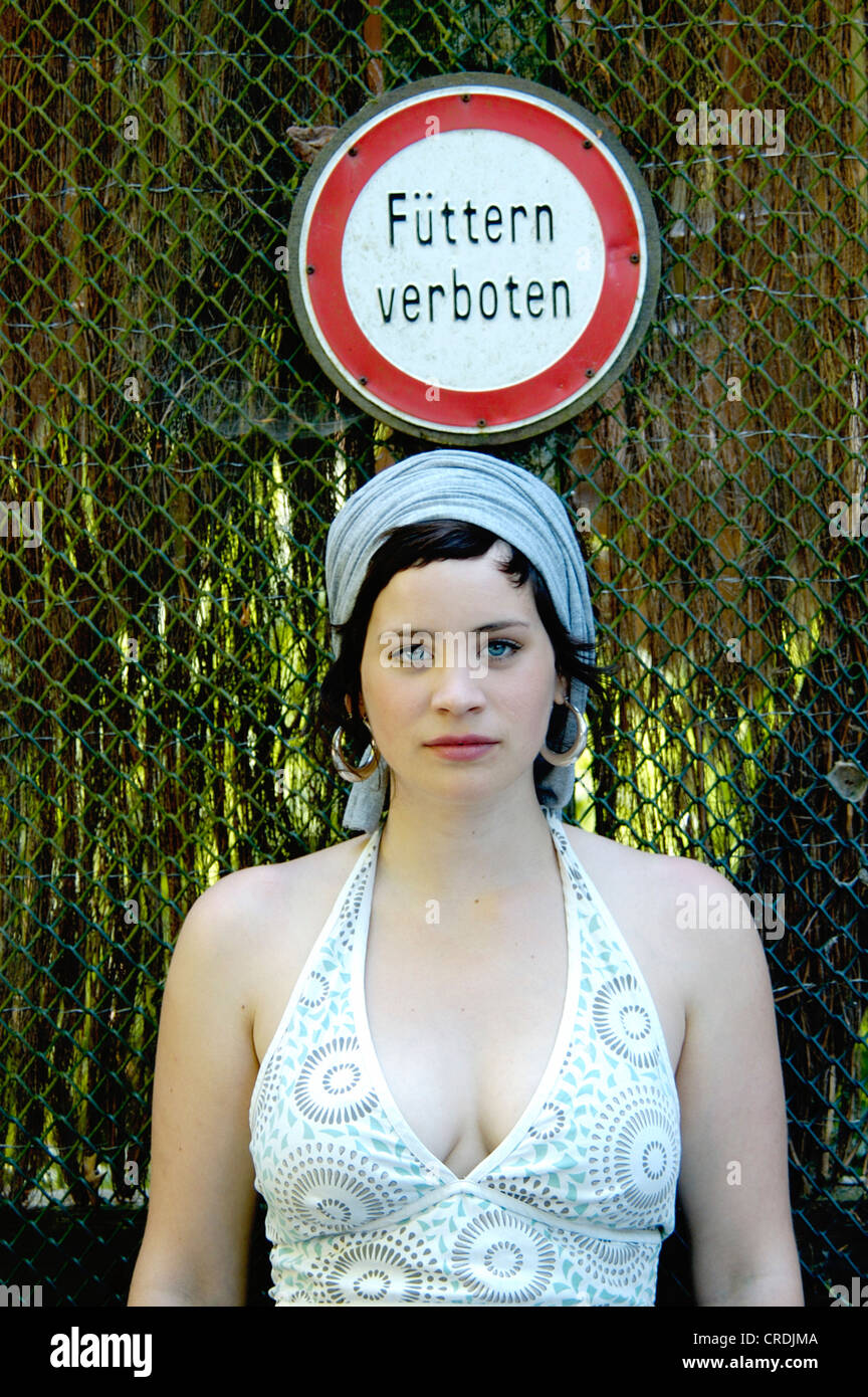 beautiful woman standing under a feading forbidden information sign, Germany, North Rhine-Westphalia, Bielefeld Stock Photo