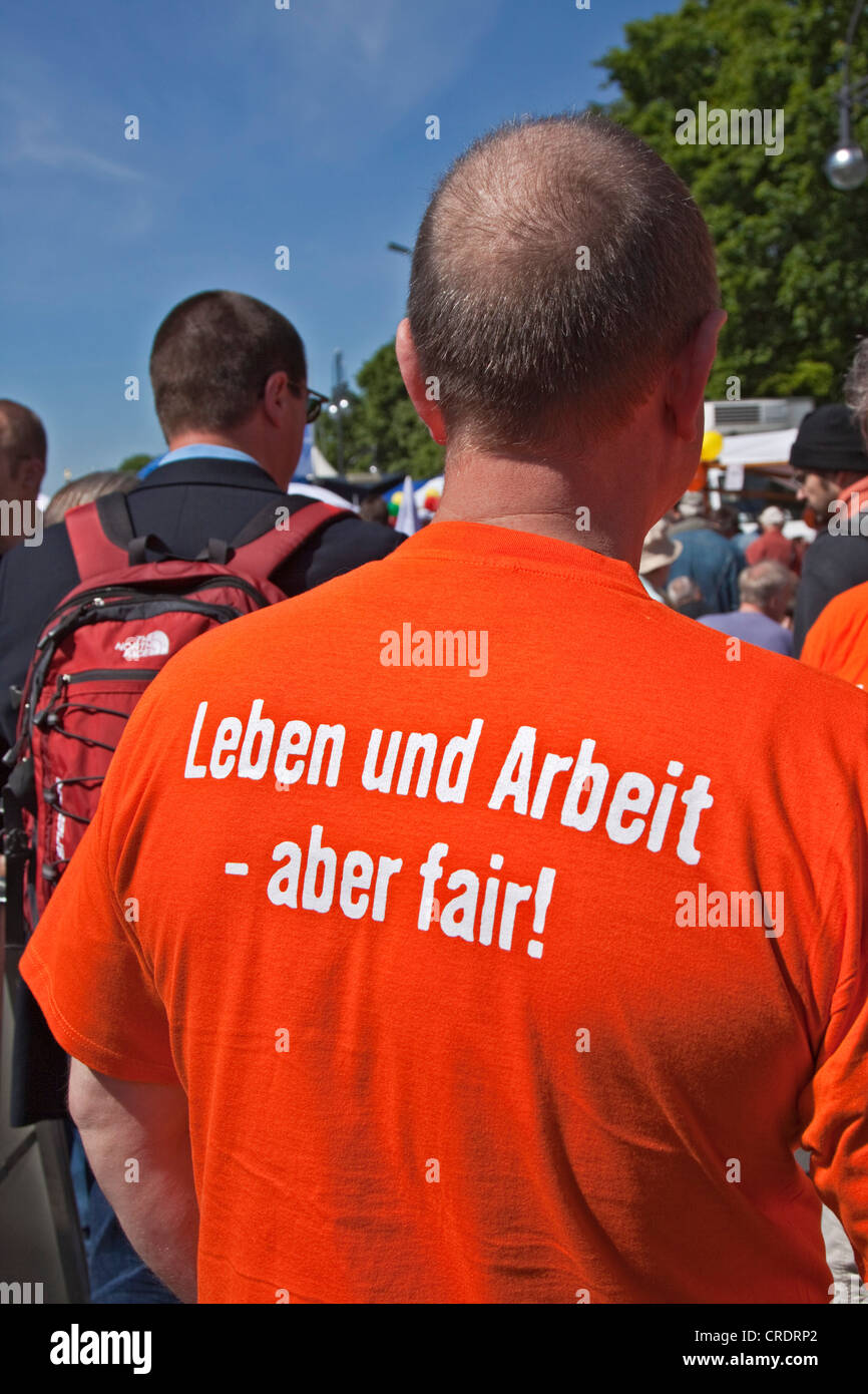 Writing 'Leben und Arbeit - aber fair!' or 'life and work - but fair!' on the back of an orange T-shirt Stock Photo