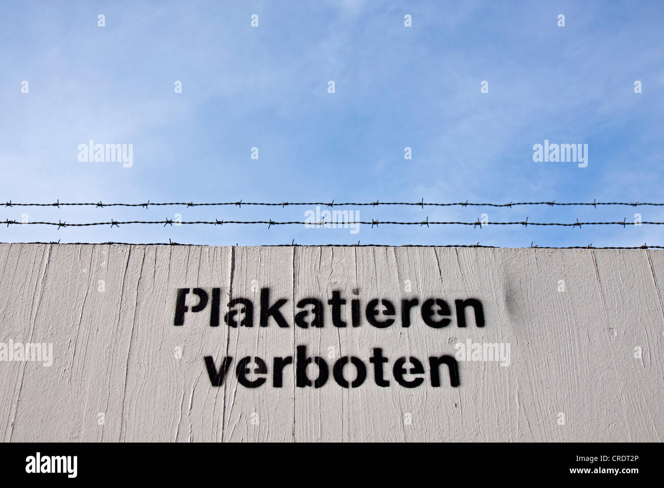 Sprayed-lettering 'Plakatieren verboten' or 'no posters' on a fence with barbed wire Stock Photo