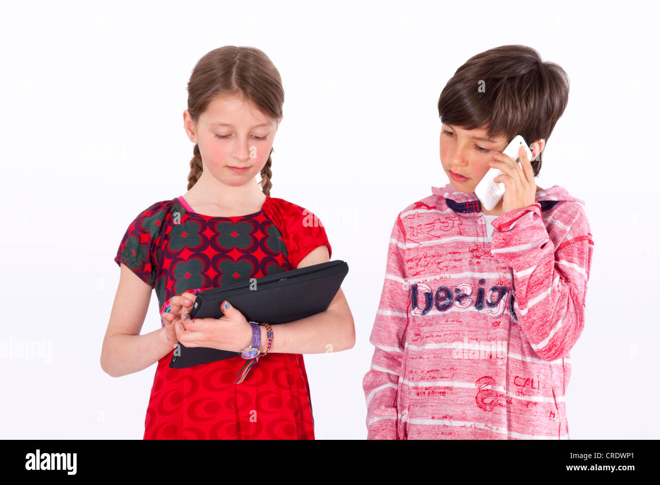 Girl and boy, 9 years, with mobile phone and iPad Stock Photo