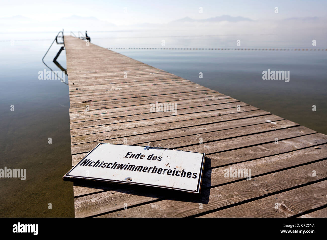 Jetty with a sign 'Ende des Nichtschwimmerbereichs', German for 'end of the non-swimmer area', seated woman at back Stock Photo