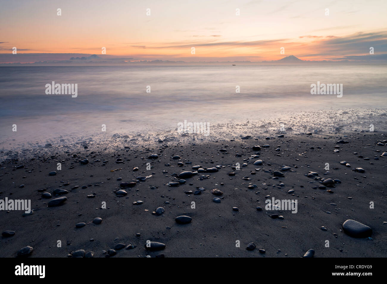 View towards volcanic mountains from the beach at Whiskey Gulch, left, Mount Iliamna, and right, Mount Redoubt, Cook Inlet Stock Photo