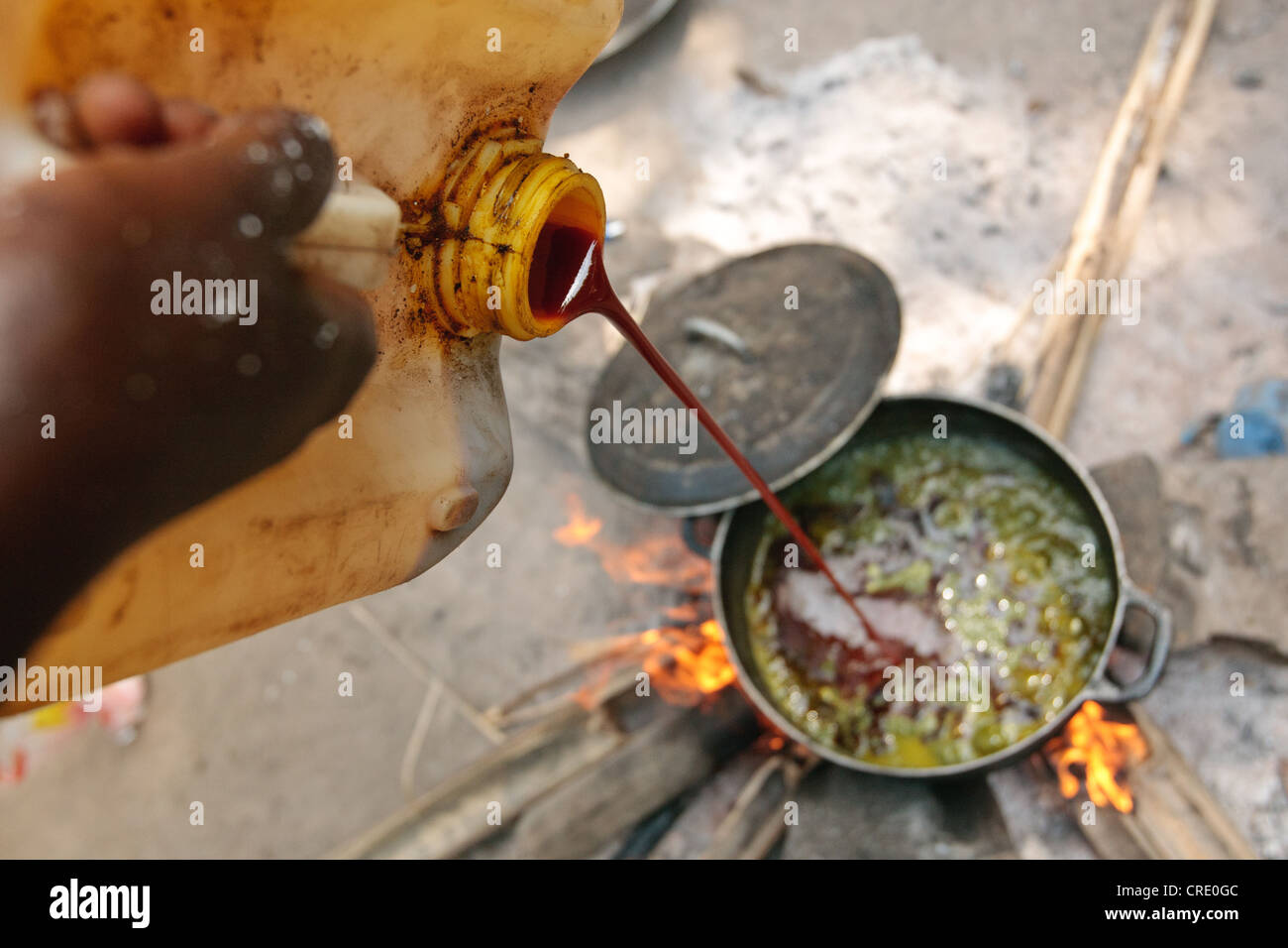 Edith Saysay, 35, pours palm oil into a pot as she cooks in the village of Jenneh, Bomi county, Liberia Stock Photo