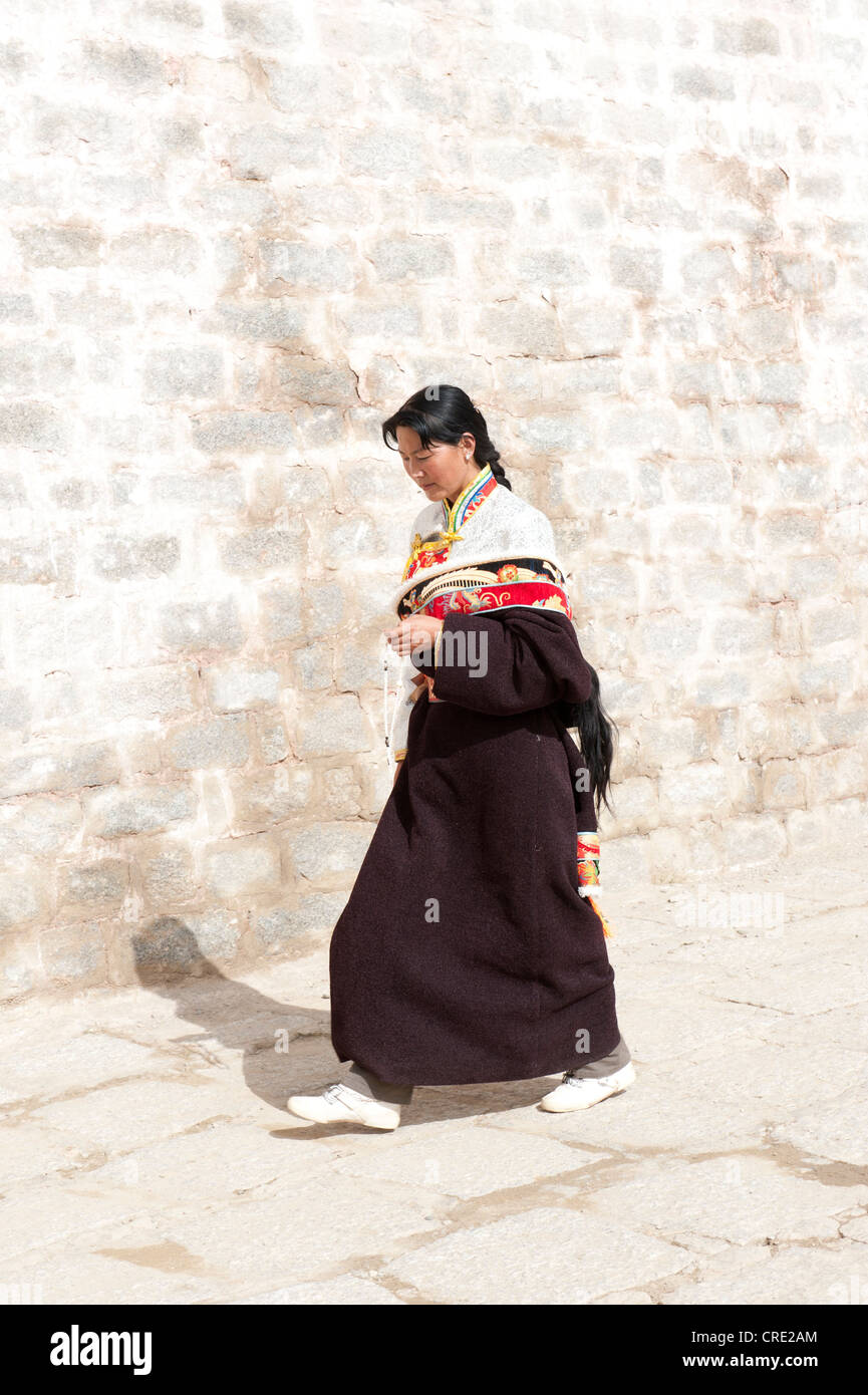 Tibetan Buddhism, young religious Tibetan woman walking along a wall, Ganden monastery, Himalaya Range, central Tibet, Ue-Tsang Stock Photo