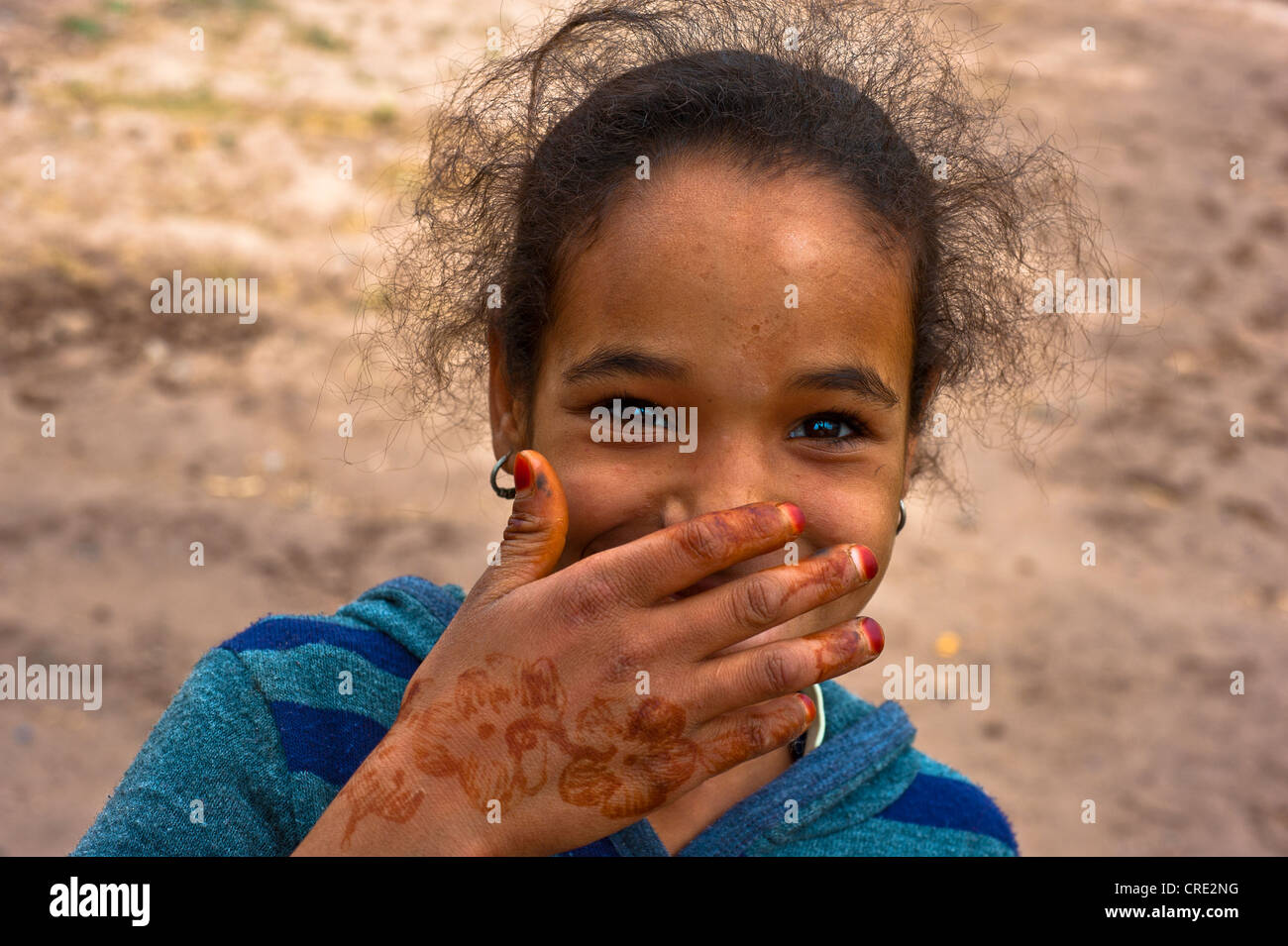 Portrait, smiling girl holding her hand decorated with henna patterns in front of her mouth, Skoura, Morocco, Africa Stock Photo