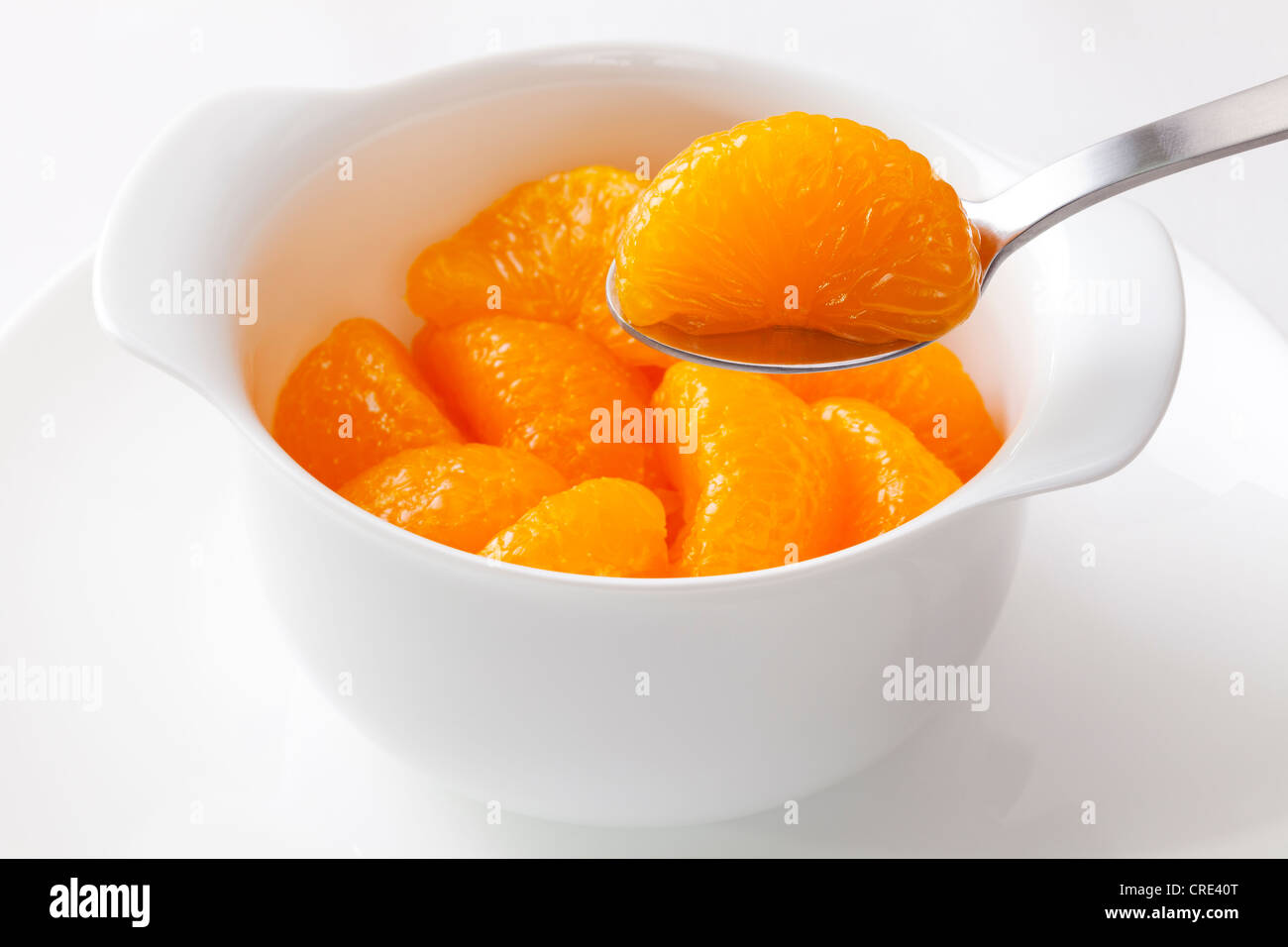 Mandarin oranges from a can, one segment being lifted with a spoon