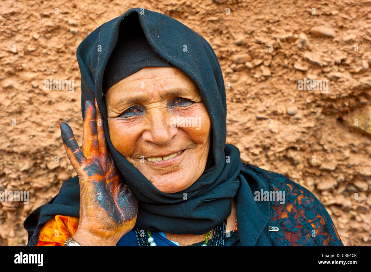 Portrait of a kindly old woman wearing a black head scarf, the palm of her hand with henna is traditionally colored black cave Stock Photo