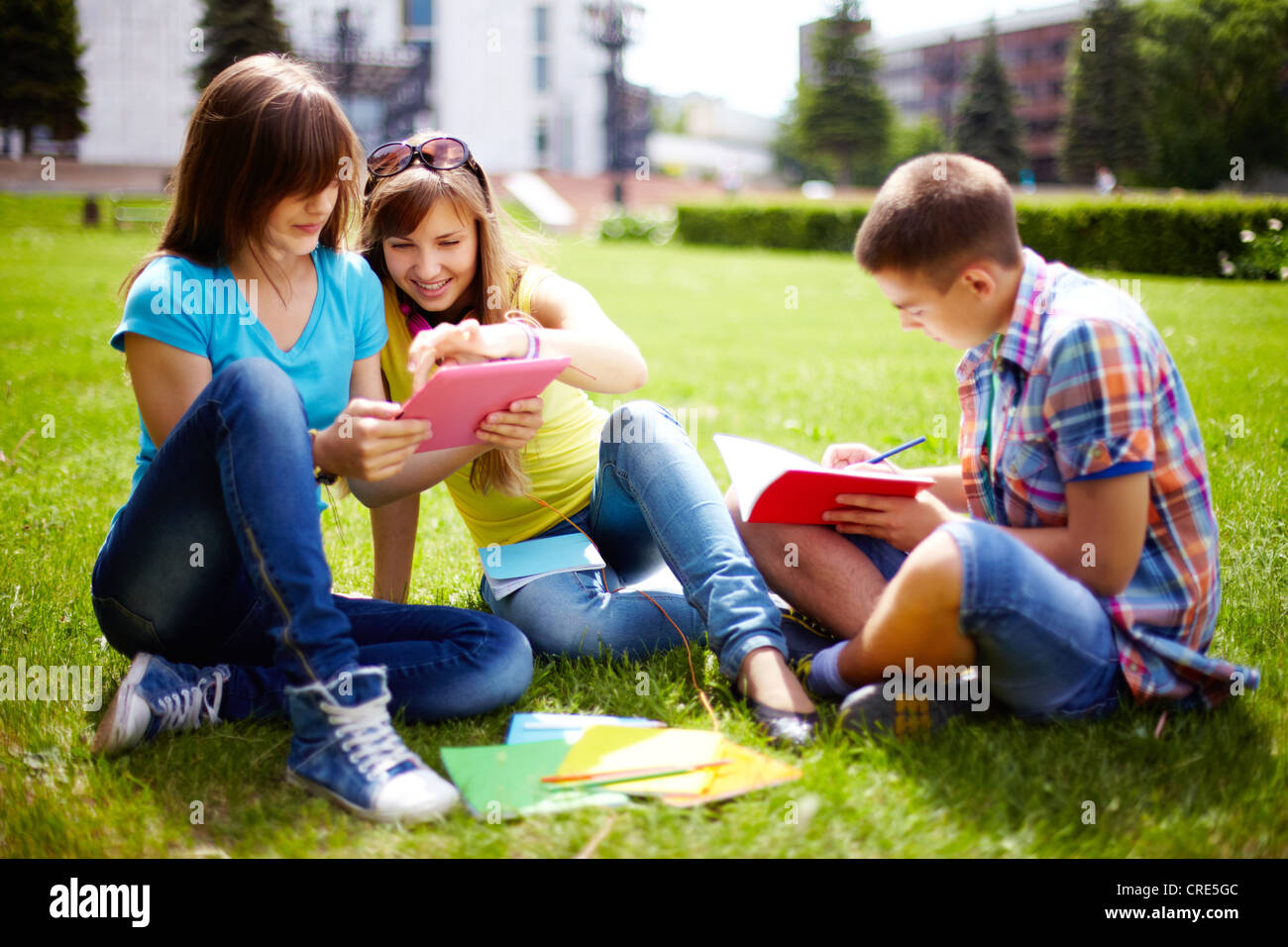 Cute high-school students doing homework outdoor on the lawn Stock Photo