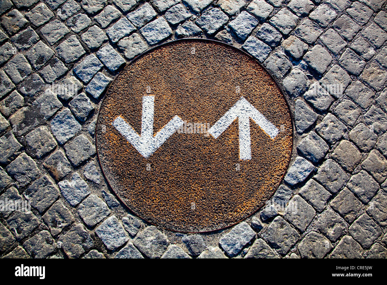 Directional arrows for cyclists on a rusty manhole cover on the ground in the district of Belem in Lisbon, Portugal, Europe Stock Photo