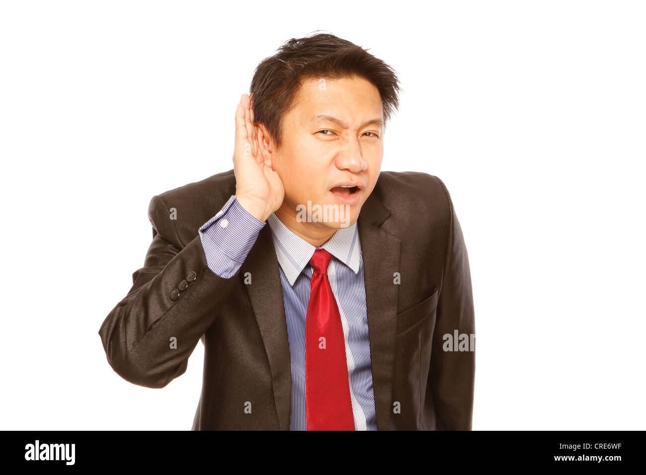 Young man in business attire cupping his ear and trying to listen Stock Photo