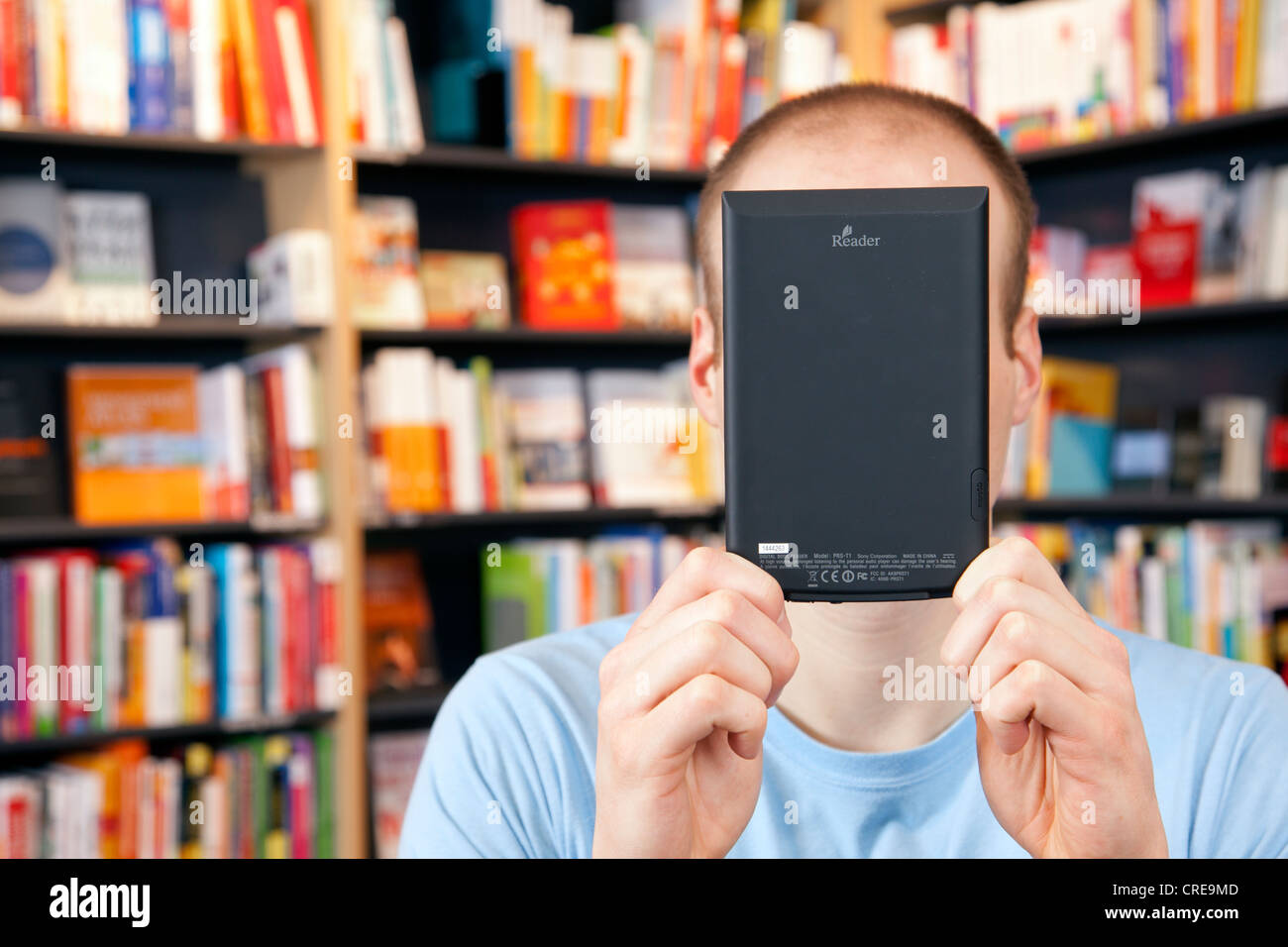 Man holding an electronic book or e-book reader, in front of his face, in a bookstore in Regensburg, Bavaria, Germany, Europe Stock Photo