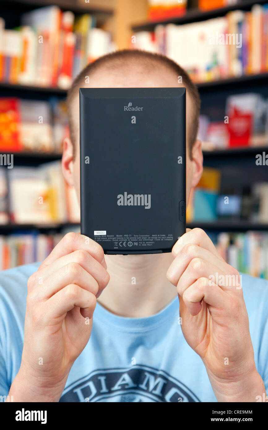 Man holding an electronic book or e-book reader, in front of his face, in a bookstore in Regensburg, Bavaria, Germany, Europe Stock Photo