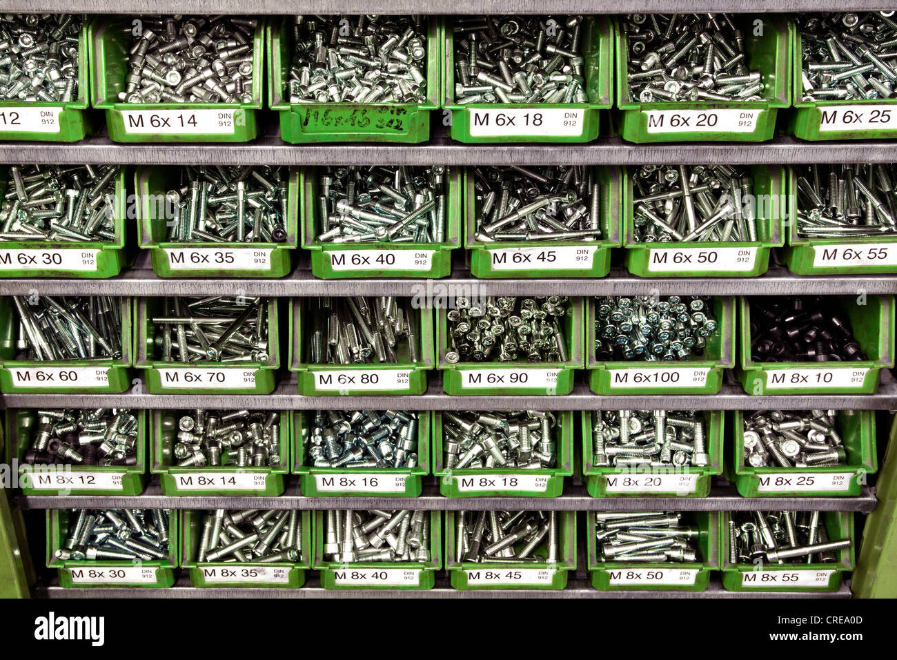 Screws of various sizes in plastic containers on a shelf Stock Photo
