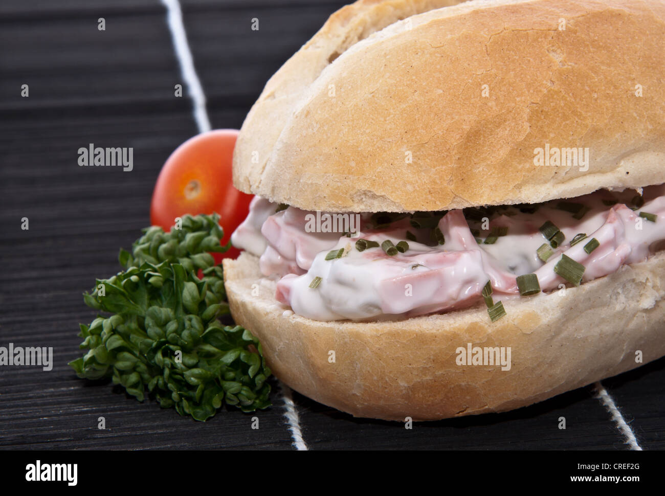 Rolls with meat salad decorated with some parsley on black tablecloth Stock Photo