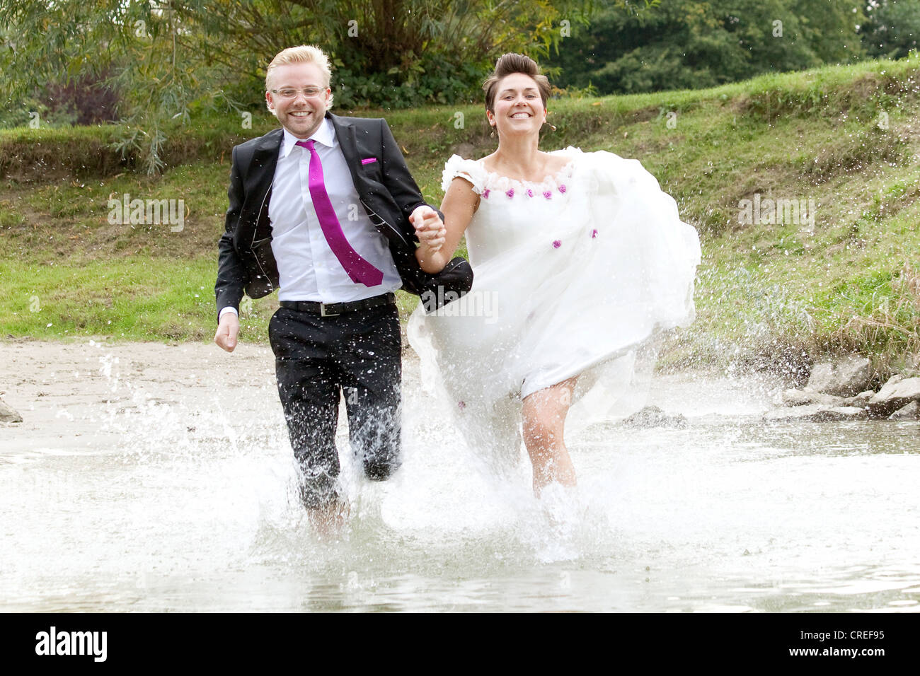 Bride in wedding dress and groom in wedding suit running into the