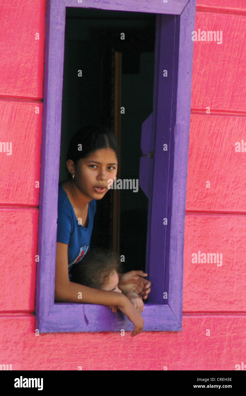 Young girl looking out of window in a red and purple hut in San Juan del Sur, Nicaragua, San Juan Del Sur Stock Photo