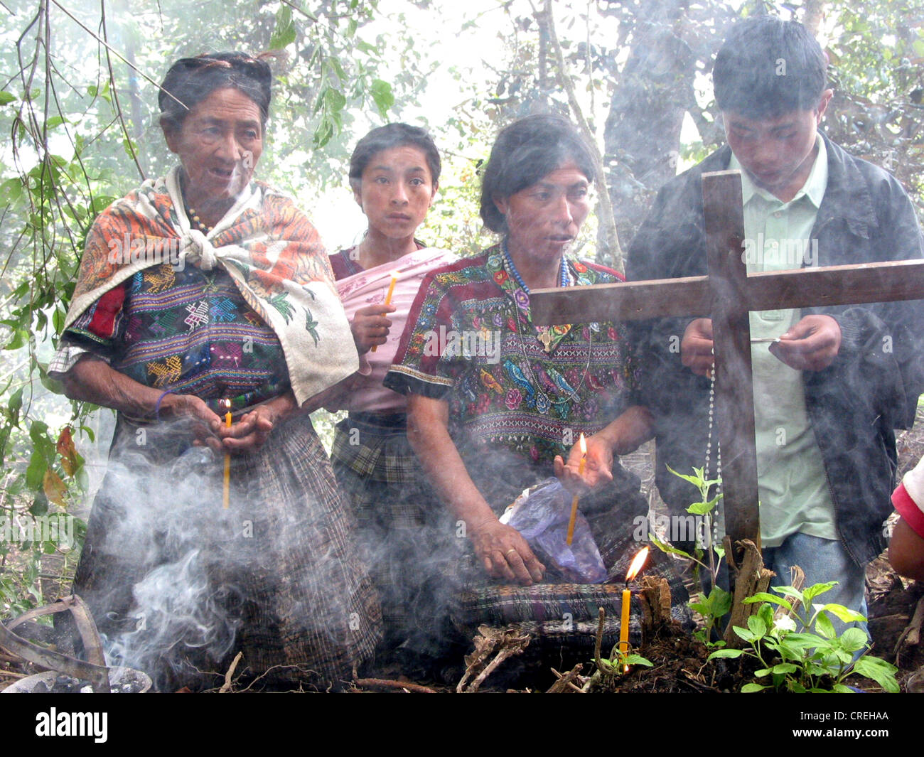 Praying Maya women and a mass grave of Maya indigenas in a forest in Comalapa, Guatemala, Quich�, Comalapa Stock Photo