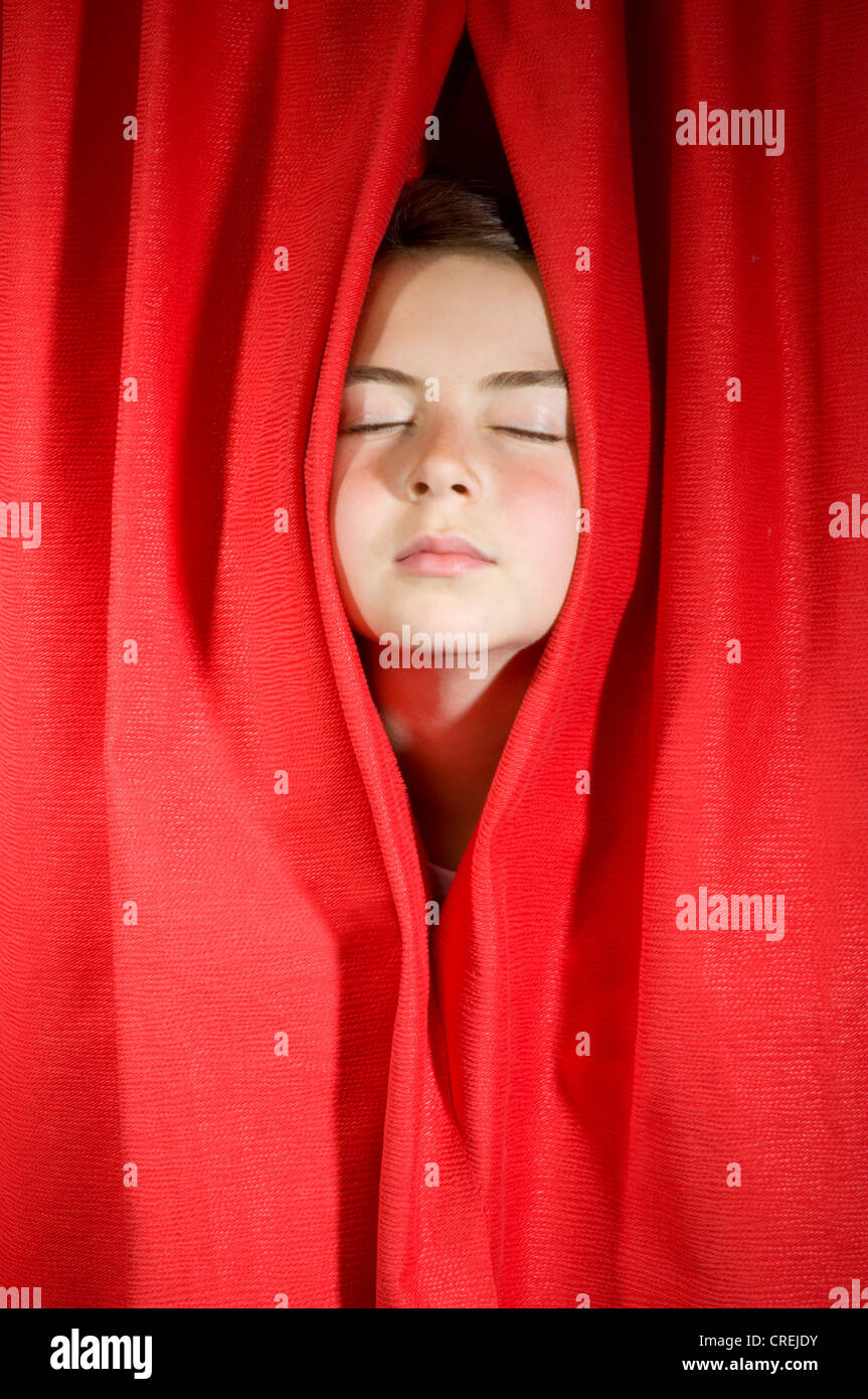 Red curtains on stage with face peering through Stock Photo
