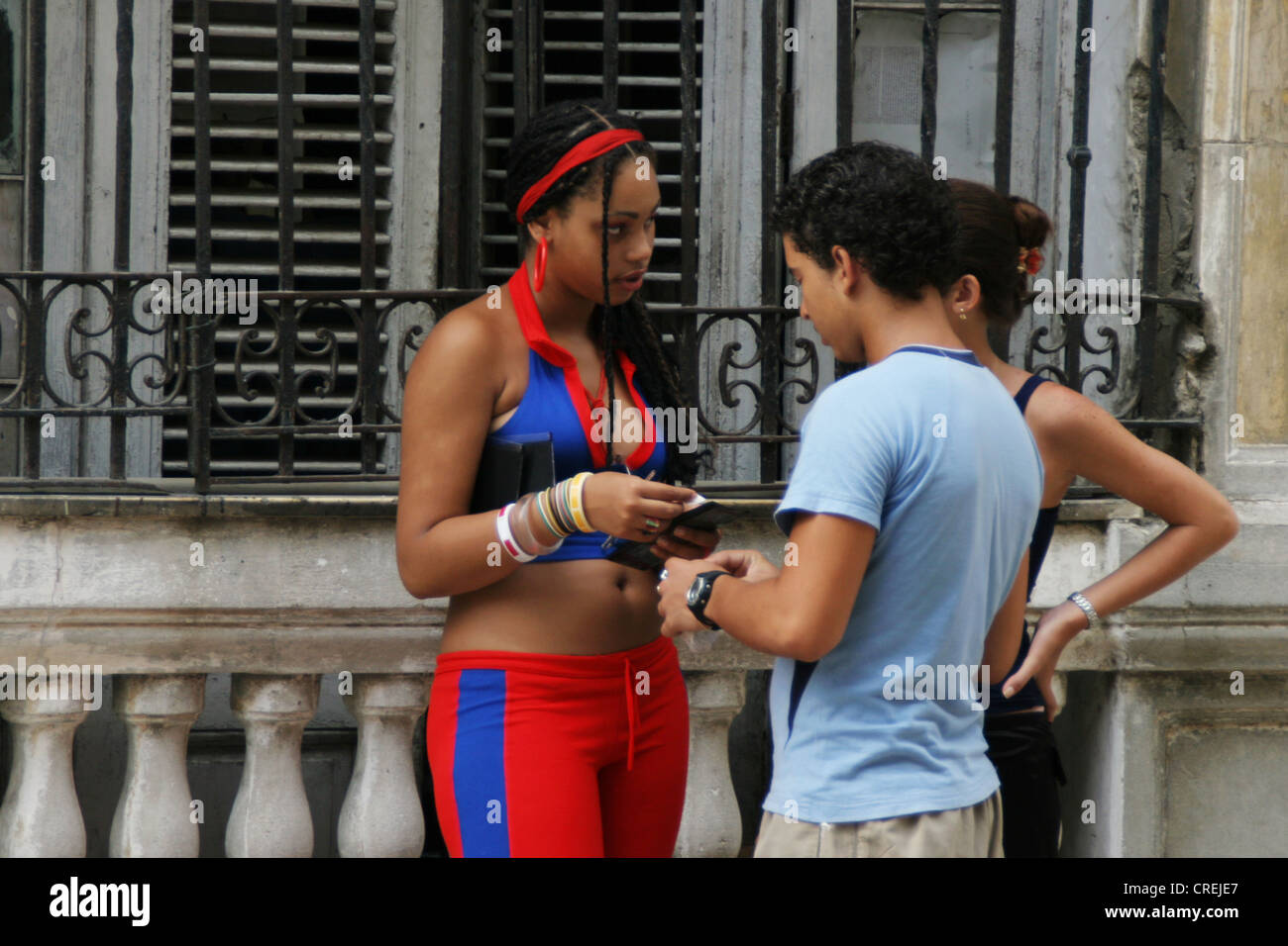 young woman in colourful clothings with friends in the old town, Cuba, La Habana Stock Photo