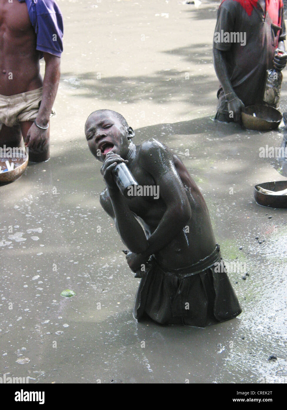 Boy with body in mud imitating a reporter with a microphone in a  holy place to Voodoo followers in Plaine du Nord, Haiti, Plaine du Nord Stock Photo