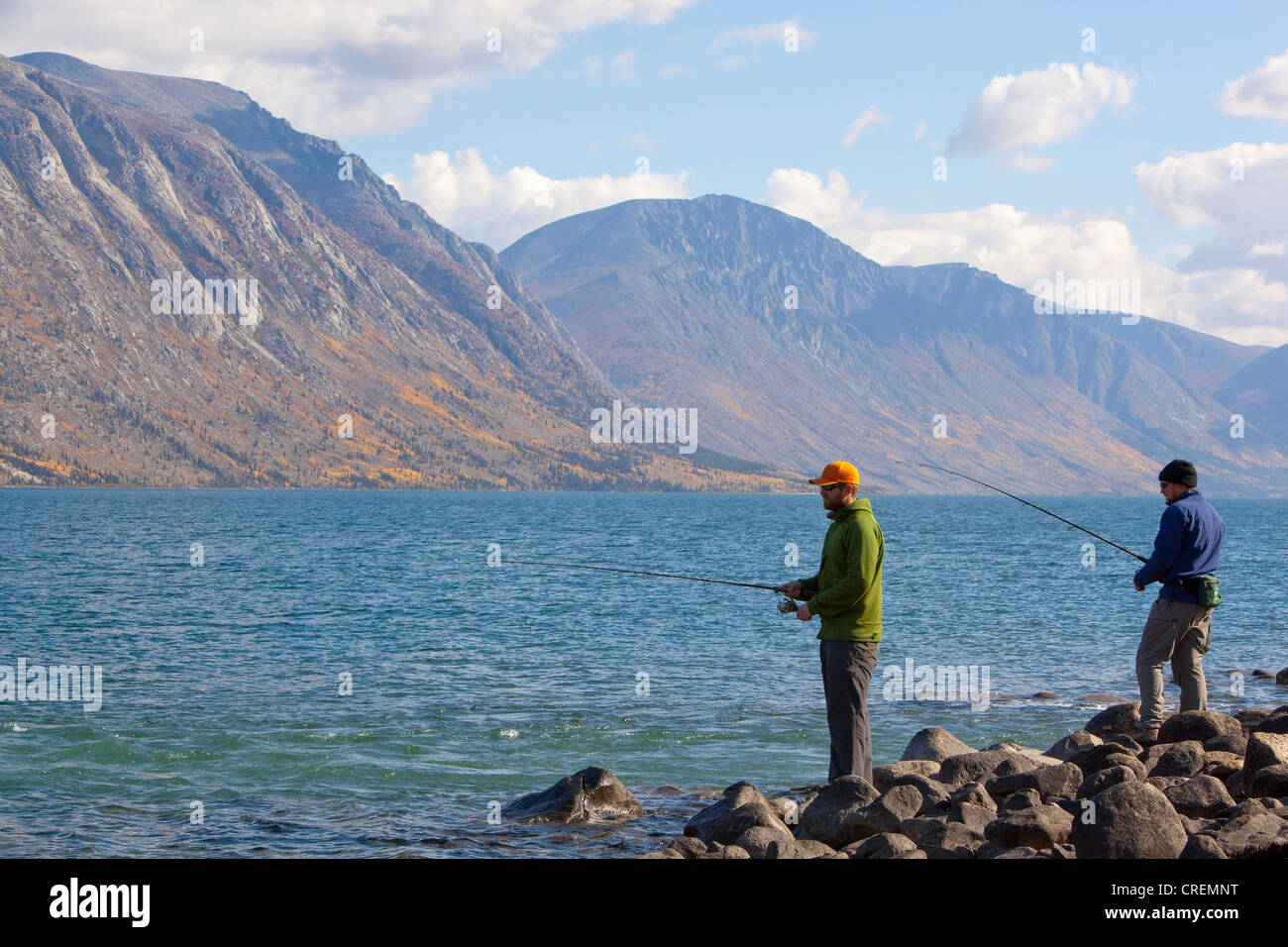 Two men spin fishing, Kusawa Lake, mountains behind, Indian summer, leaves in fall colours, autumn, Yukon Territory, Canada Stock Photo