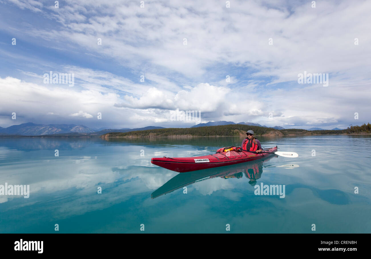 Young woman in a sea kayak, paddling, sea kayaking, mountains behind