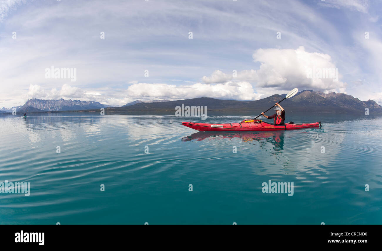 Young woman in a sea kayak, paddling, sea kayaking, mountains behind