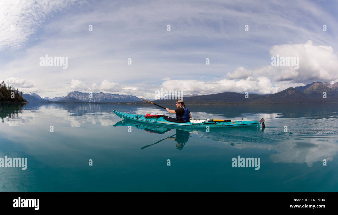 Young woman in a sea kayak, paddling, sea kayaking, mountains behind