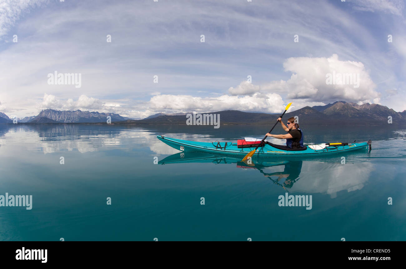 Young woman in a sea kayak, paddling, sea kayaking, mountains behind