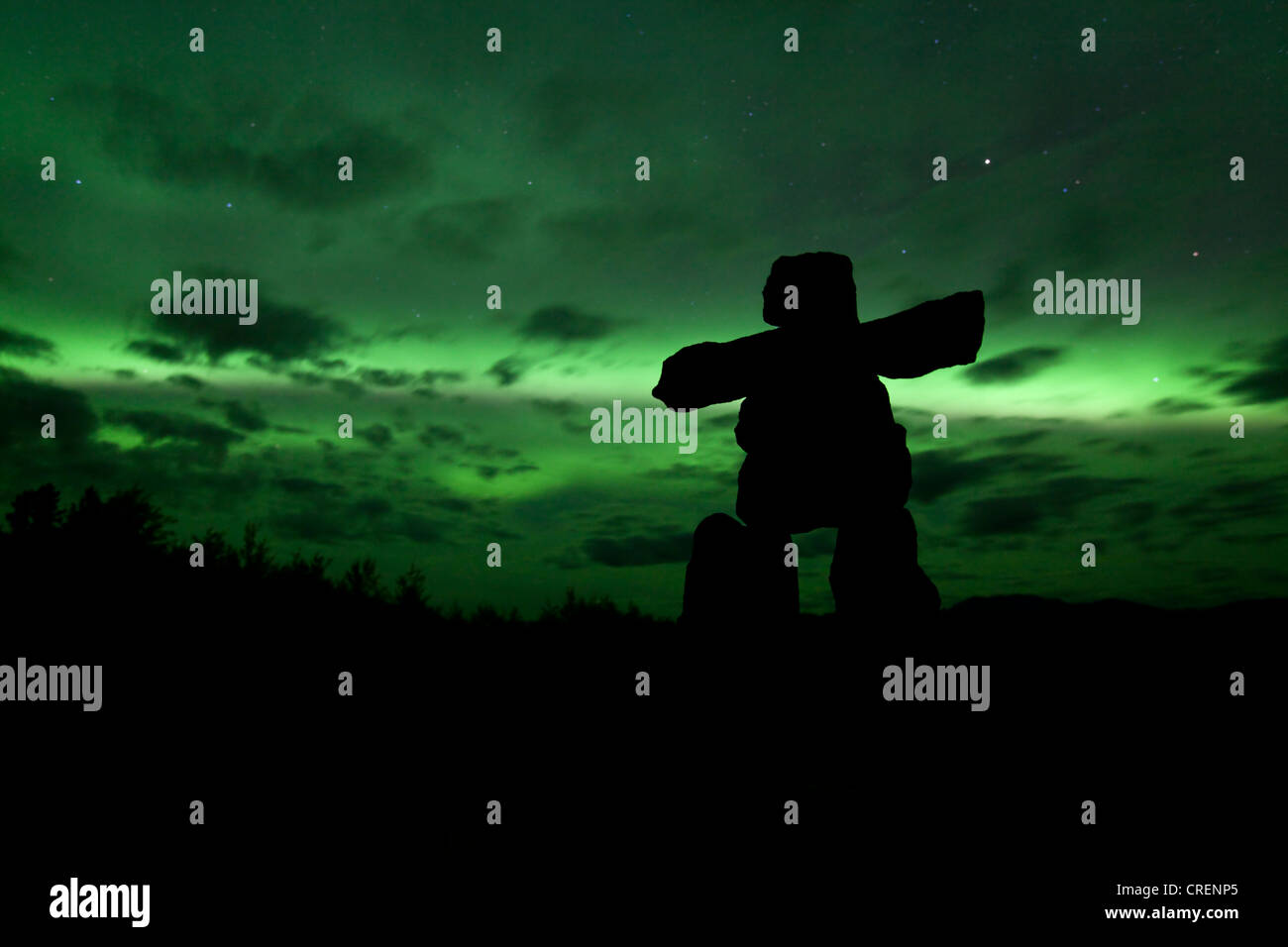 Silhouette of Inuit stone man, inukshuk, inuksuk, stone landmark or cairn, northern polar lights, Aurora Borealis, green Stock Photo