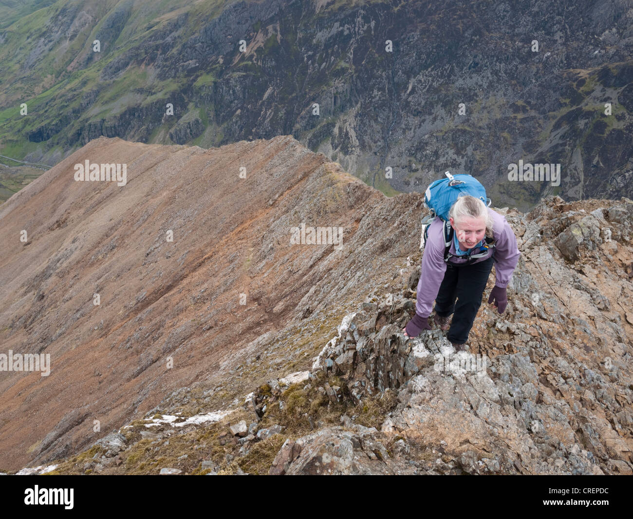 A female hillwalker reaches the top of the north ridge approach to Crib Goch - the classic arete approach to Snowdon Stock Photo