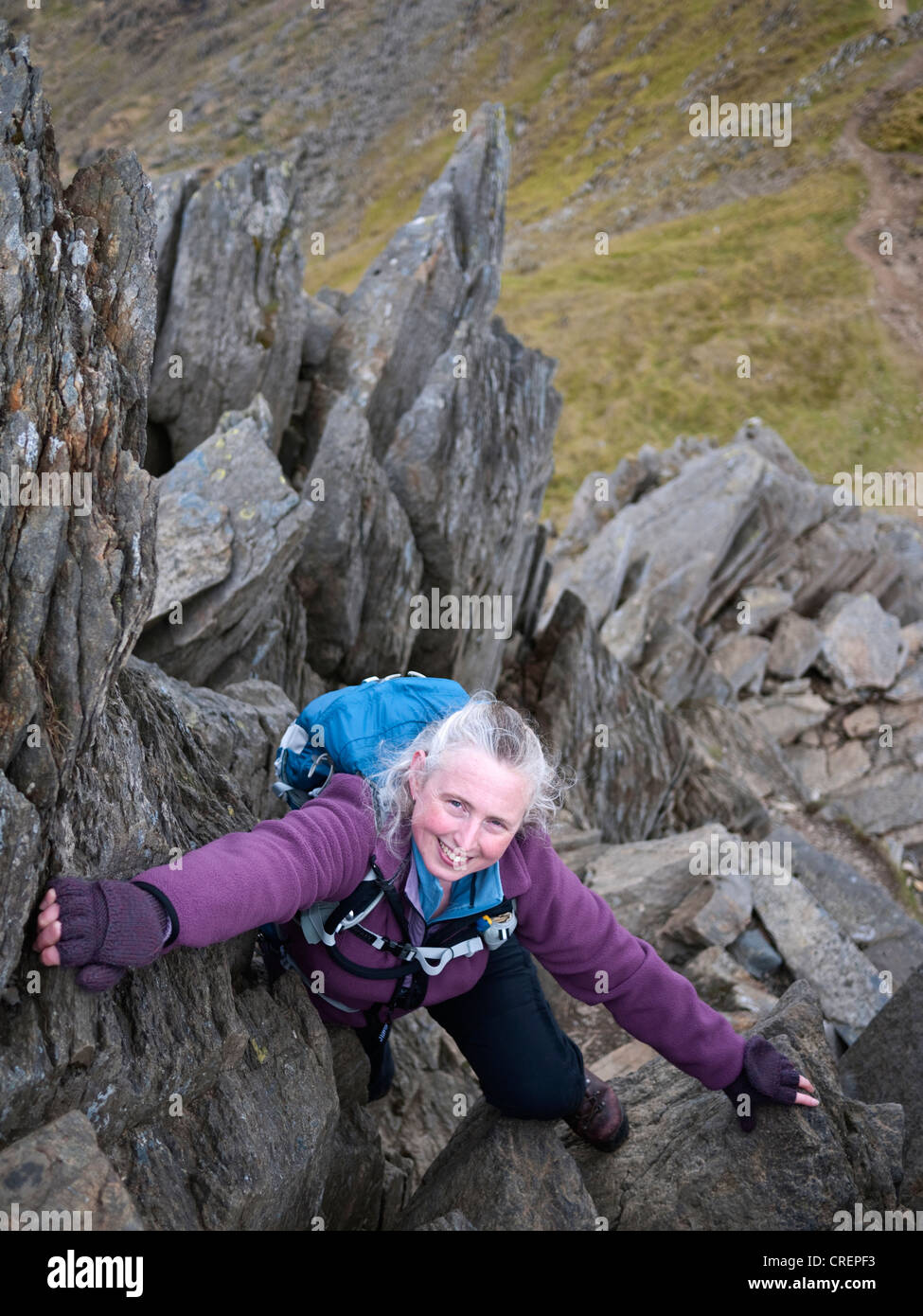 A female hill walker scrambling on Crib y Ddysgl part of the classic Snowdon Horseshoe route