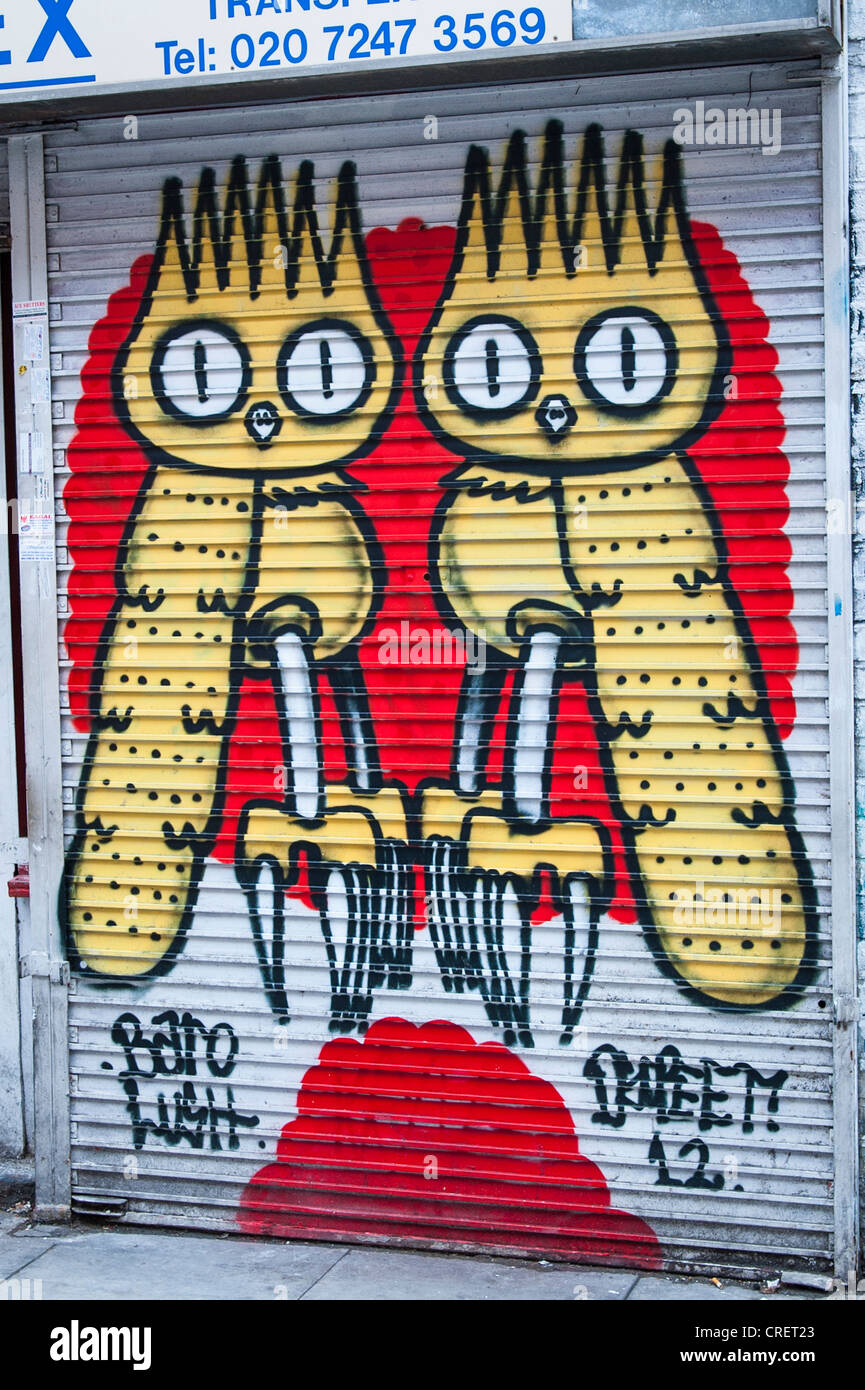 London East End Brick Lane graffiti street art mural yellow owl like birds on shop store blind Baro Lush Australian Dscreet 12 Stock Photo