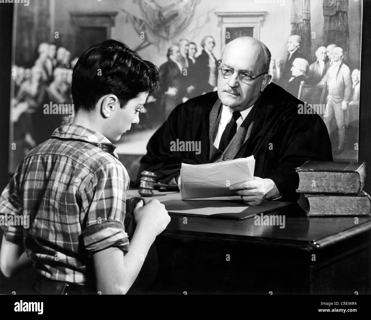 Judge sitting at his desk talking to a boy Stock Photo