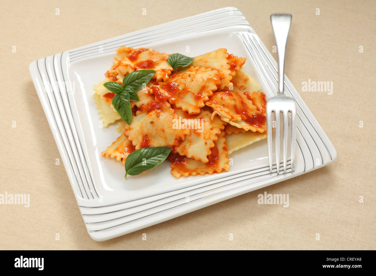 Plate of ravioli with tomato sauce and a garnish of basil leaves Stock ...