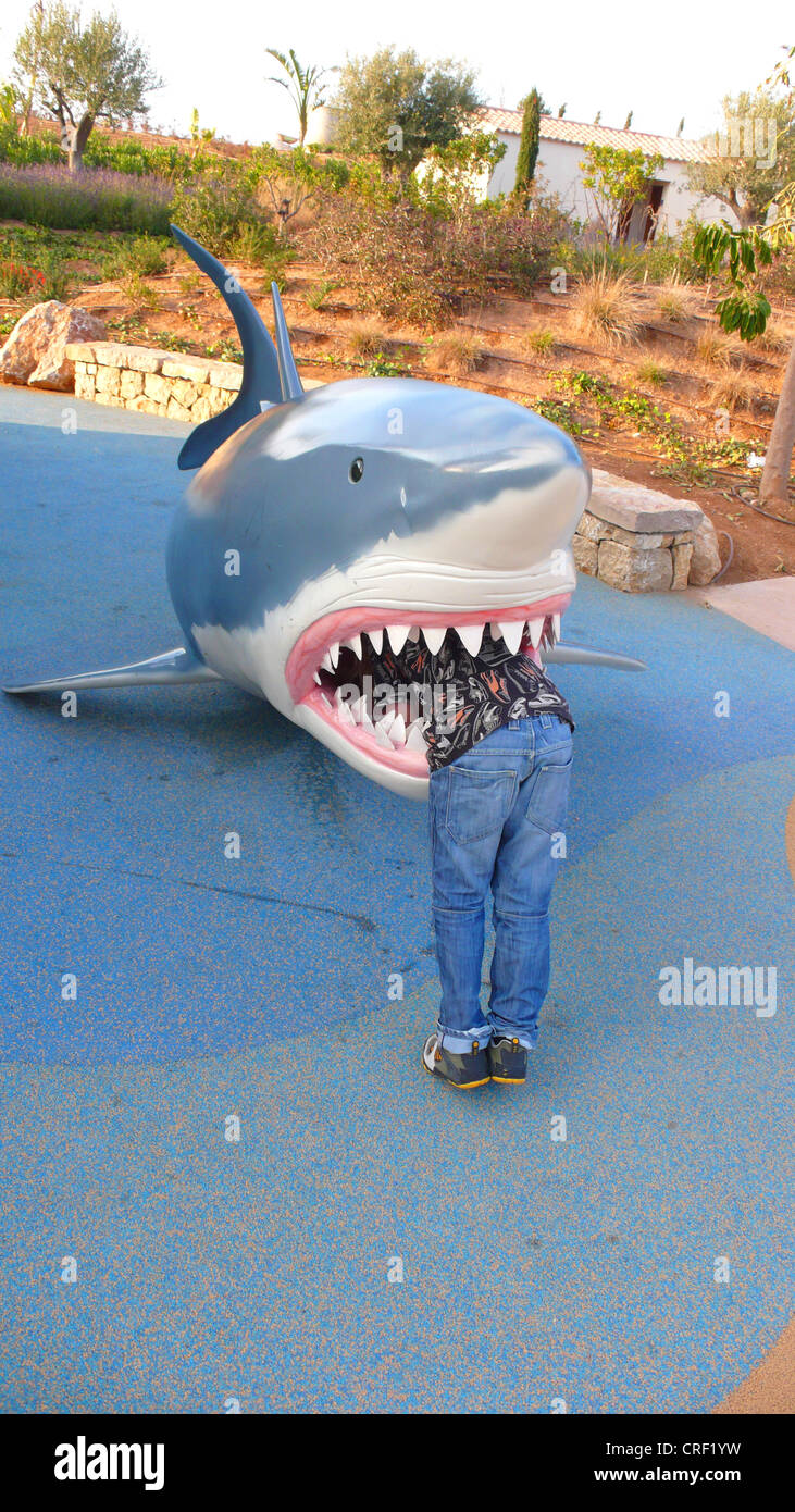 great white shark (Carcharodon carcharias, Carcharodon rondeletii), boyin the mouth, dummy on a children�s playground Stock Photo
