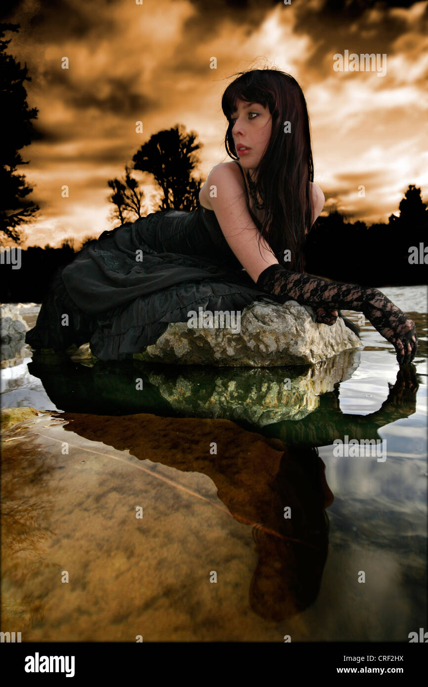 young woman lying on a stone at the water Stock Photo